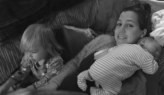 mother reading evidence based hypnobirthing book with toddler and baby on her.