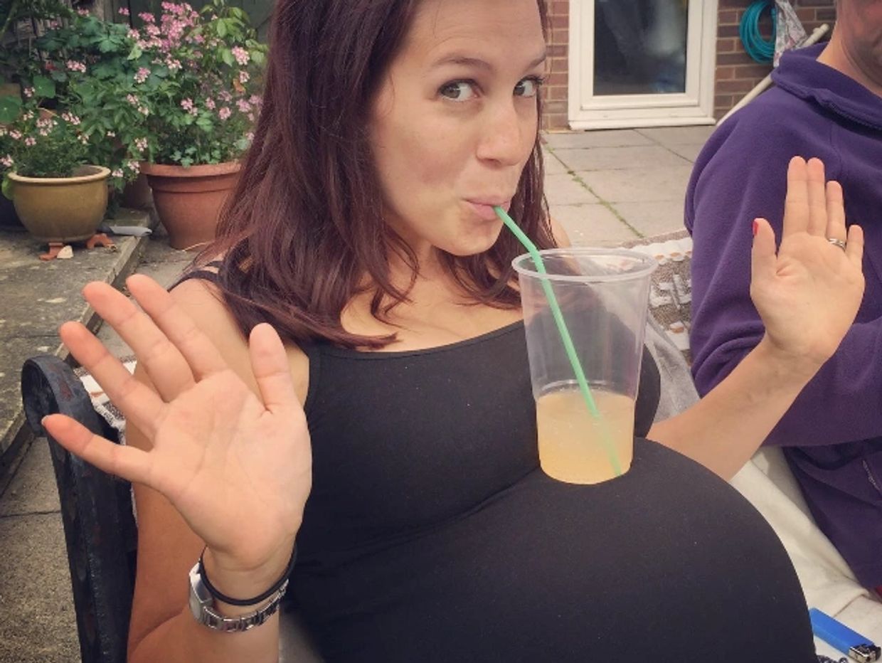 Pregnant person balancing drink on a large bump during Hypnobirthing classes
 in east sussex
