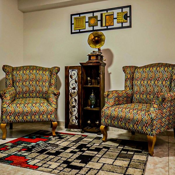 Two patterned armchairs with a vintage gramophone and decorative shelf in between.