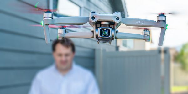 Drone flying in front of a man outdoors.