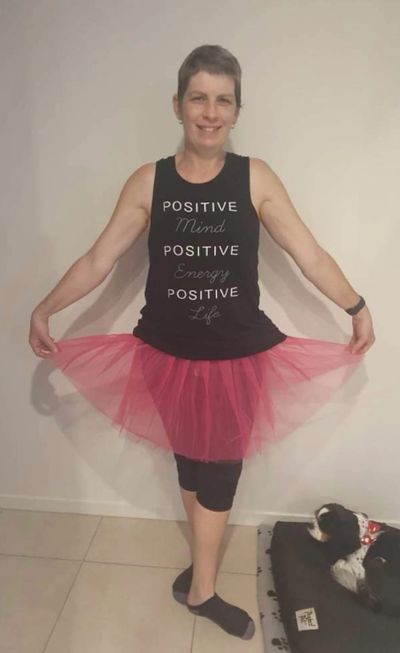 Breast cancer surviver standing in a pink tutu with a positive shirt on