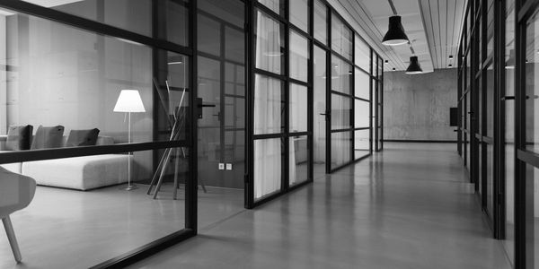 Modern office hallway with glass walls and minimalist furniture.