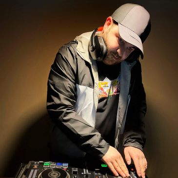DJ in a cap mixing music on a turntable.