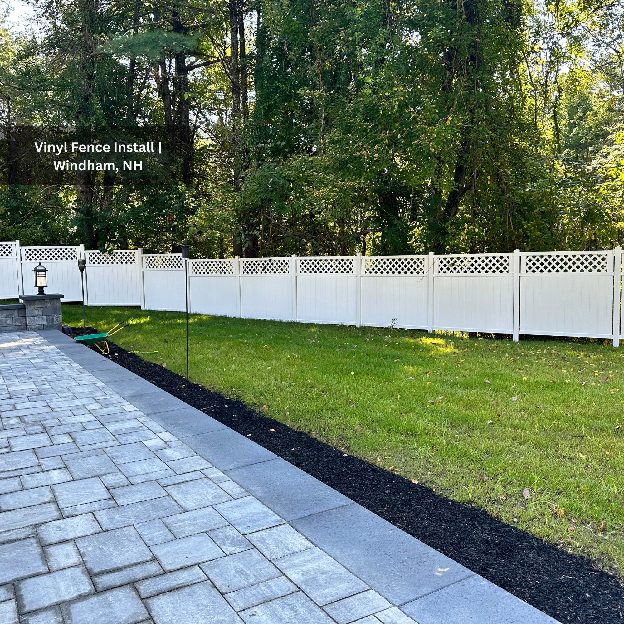 Newly installed white vinyl fence in a green backyard in Windham, NH.