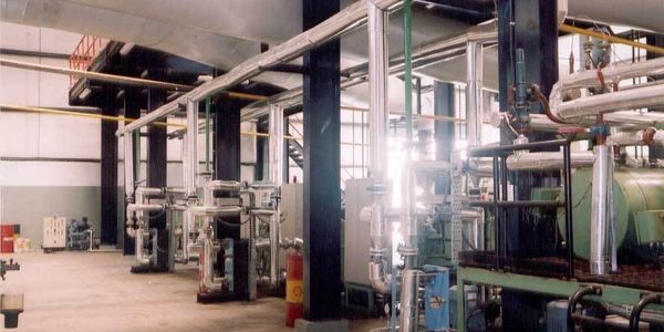 Industrial machinery and piping inside a large factory building.