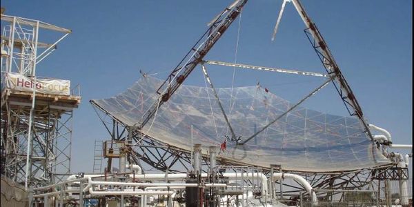 Large solar energy collector dish under clear blue sky.