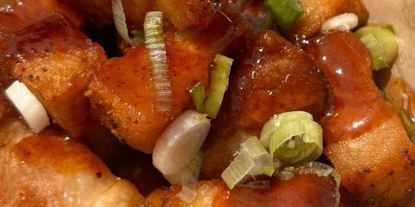 Close-up of saucy chicken bites garnished with chopped green onions.