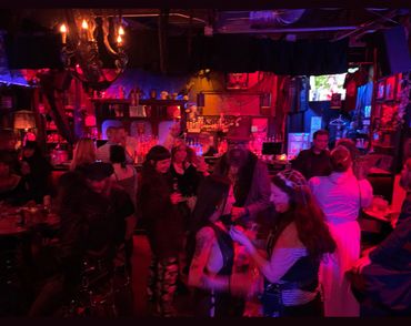 People enjoying a lively night at a dimly lit bar with red and purple lighting.