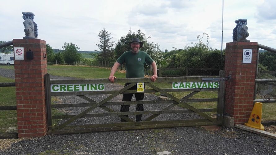 Jason, the owner of Creeting Caravans and Camping standing smiling in the gateway to the site
