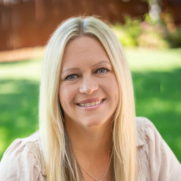Smiling woman with long blonde hair outdoors.