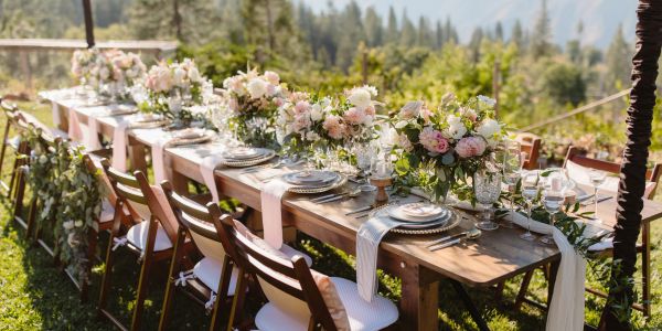 Elegant outdoor dining table set with floral centerpieces and fine tableware.
