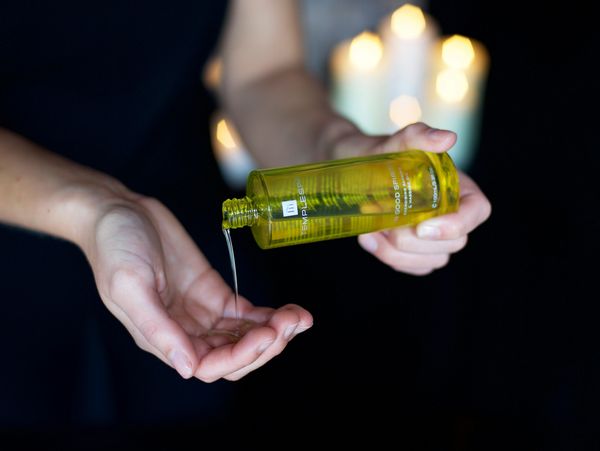 Person pouring massage oil on their hands