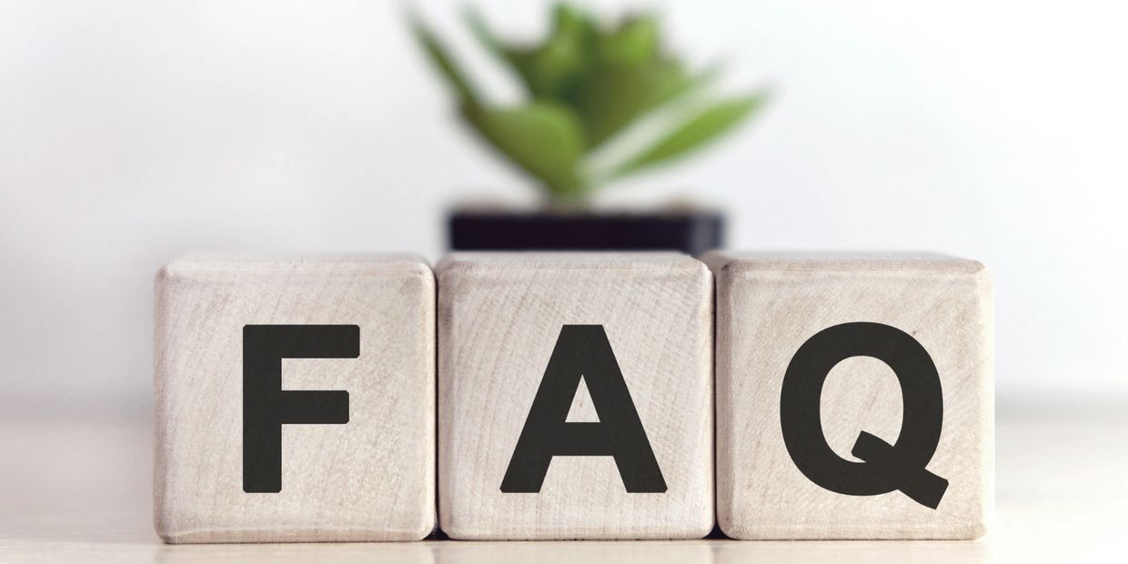 Wooden blocks spelling FAQ with a blurred plant in the background.