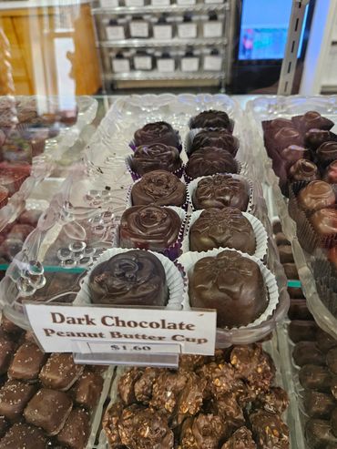 Tray of dark chocolate peanut butter cups in a display case.