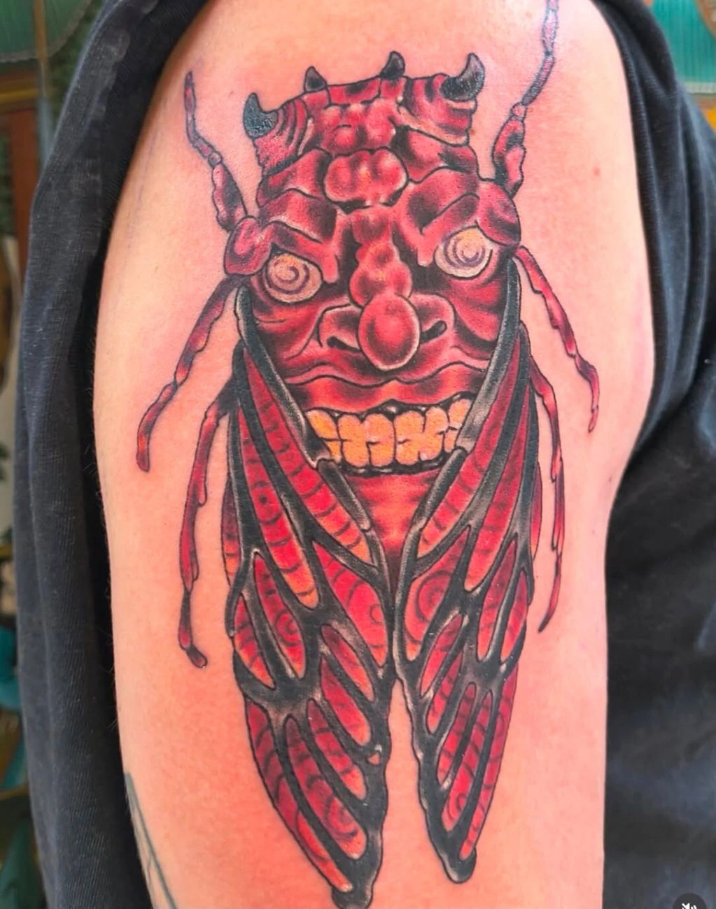 Tattoo of a red demonic cicada with detailed wings and face.