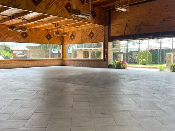 Espacio amplio con techo de madera y grandes ventanas.