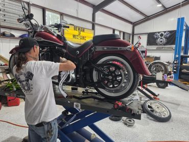 Man repairing a motorcycle in a garage.