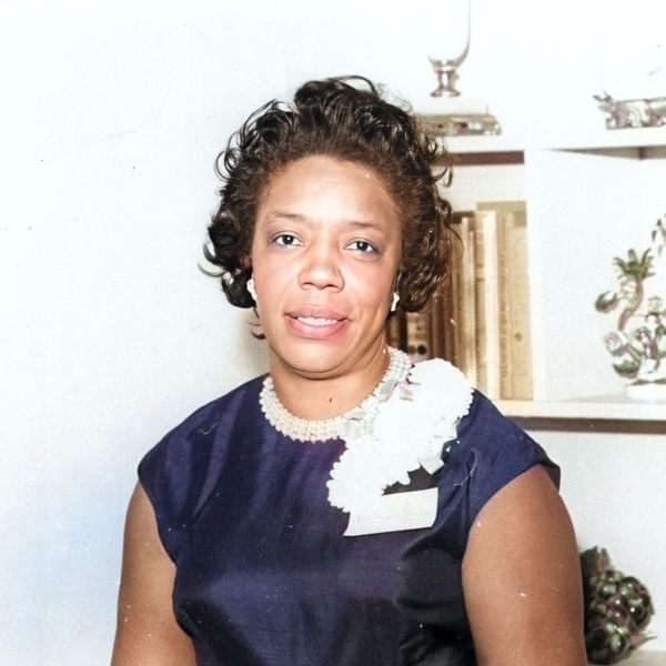 Portrait of a woman in a dark dress with pearl necklace.