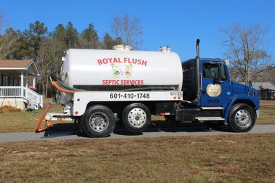 A Royal Flush Septic Services truck parked near a house on a sunny day.