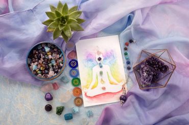 A lavender table cloth with a picture of a chakra chart and crystals on the table