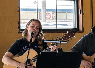 Duet performing music with guitars indoors.