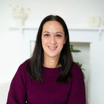 Smiling woman in a purple top with a white background.