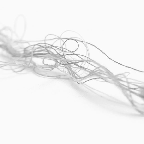 Close-up of tangled gray threads on a white surface.