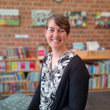 Woman smiling in a library setting.