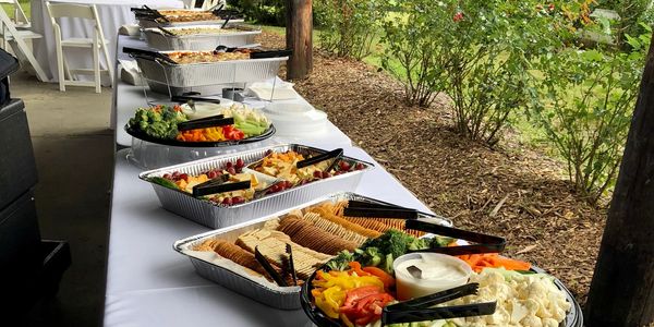 A buffet table with trays of vegetables, crackers, and dips.