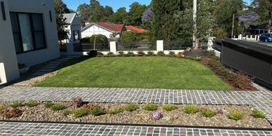 New turf lawn with stepping stone path and landscaped garden beds in a Sydney residential backyard