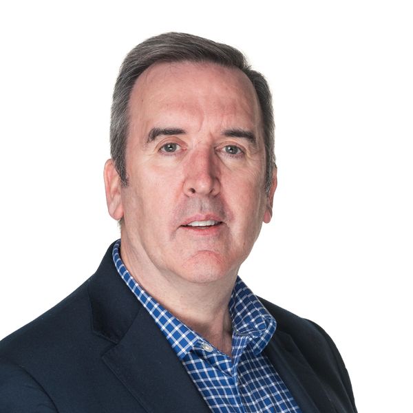 Portrait of a middle-aged man in a checkered shirt and dark blazer.