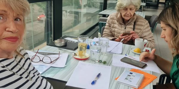 Three women at a table with papers and phones.