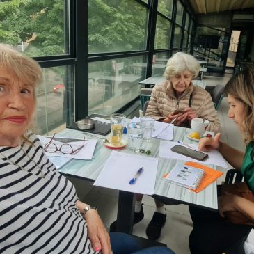 Three women gathered around a table with papers and drinks.