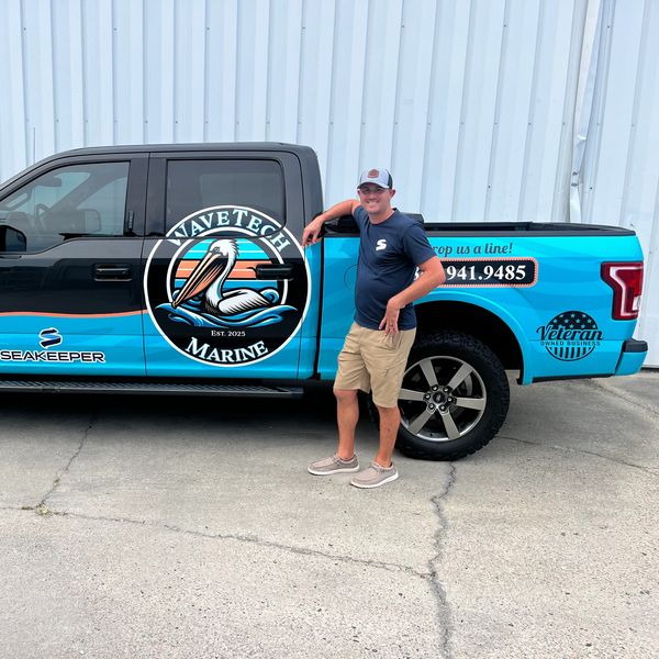 Man poses beside a blue and black WaveTech Marine branded truck.