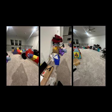 A spacious carpeted room with scattered toys, boxes, and storage bins.