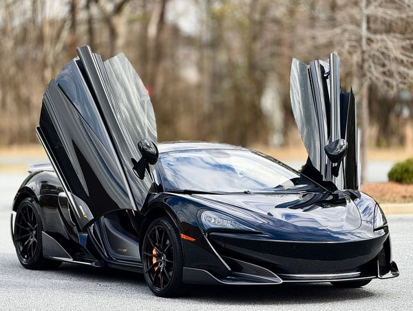 Sleek black McLaren 600LT with signature butterfly doors open.