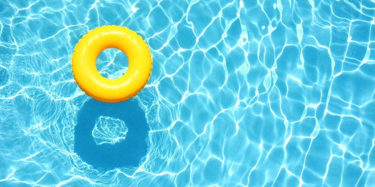 Bright yellow inflatable ring floating in a clear blue pool.
