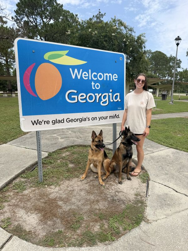 Woman with two dogs at Welcome to Georgia sign.
