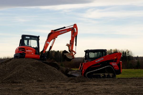 Two Kubota construction machines on a gravel mound