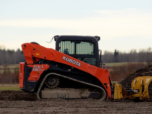 A Kubota SVL 90-2 tracked loader working on a dirt field