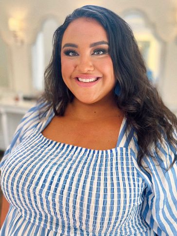 Smiling woman with long dark hair in a blue and white striped top.