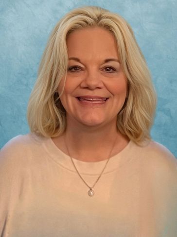 Smiling woman with blonde hair and light-colored top.