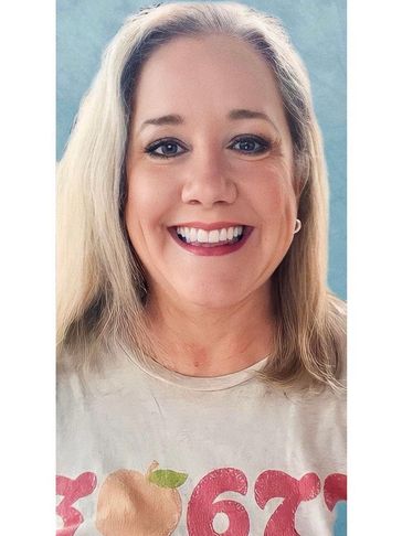 Smiling woman with blonde hair wearing a peach graphic tee.