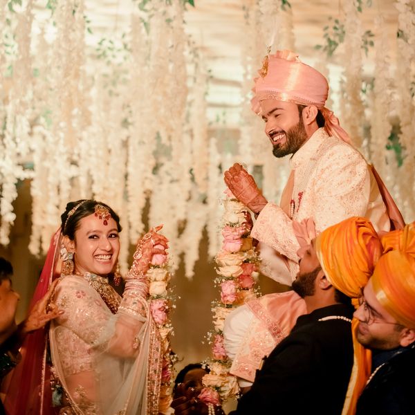 Joyful Indian couple exchanging floral garlands during wedding ceremony.