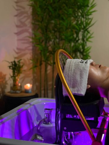 Person with towel on face enjoying a hair wash in a spa.