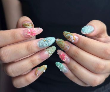 Intricate nail art with floral and pearl designs.