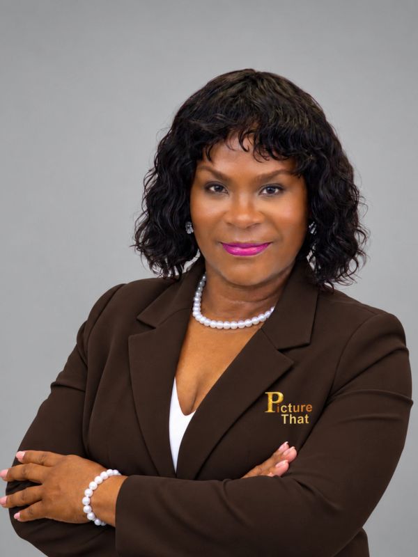 Confident woman in brown suit with pearl necklace and bracelet.