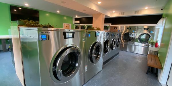 Modern laundromat with stainless steel washers and dryers in a bright, clean room.