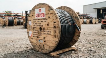 Large wooden spool with electrical cable outdoors.
