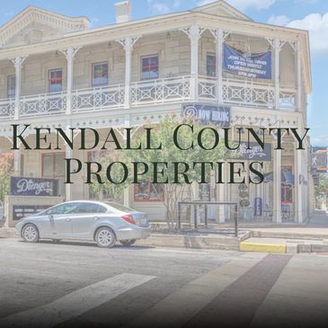 Historic building with parked car and Kendall County Properties text.